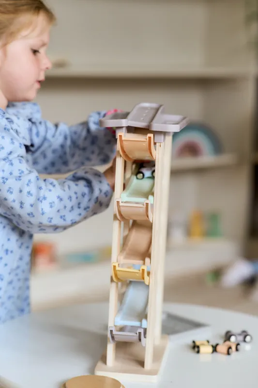 A little girl playing with a wooden car run in the play space at The Willow Bean